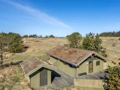 a small green building in the middle of a field at Holiday Home Alfrik - 900m from the sea by Interhome in Blokhus
