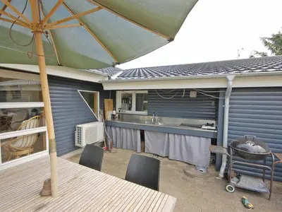 an outdoor patio with a table and an umbrella at Holiday Home Tajo - 1km from the sea by Interhome in Blokhus