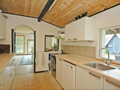a kitchen with white cabinets and a wooden ceiling at Holiday Home Tajo - 1km from the sea by Interhome in Blokhus
