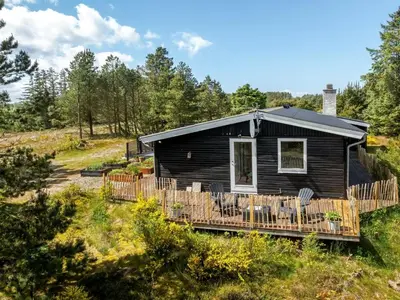 a cabin in the woods with a deck and chairs at Holiday Home Noralee - 3-5km from the sea by Interhome in Blokhus