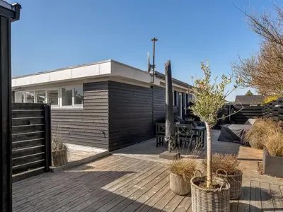 a house with a wooden deck with a tree at Holiday Home Ozan - 400m from the sea by Interhome in Blokhus