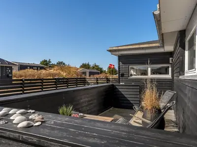 a deck with a bench on the side of a house at Holiday Home Ozan - 400m from the sea by Interhome in Blokhus