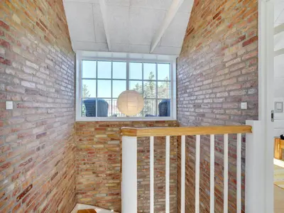 a brick walled room with a window and a staircase at Holiday Home Shiva - 300m from the sea by Interhome in Blokhus