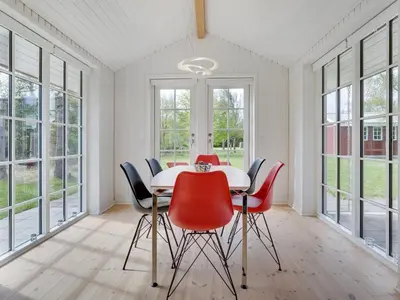a dining room with a table and red chairs at Holiday Home Ansberga - 1km from the sea by Interhome in Blokhus