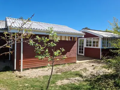 a home with a red house with a porch at Holiday Home Ansberga - 1km from the sea by Interhome in Blokhus