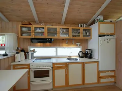 a kitchen with wooden cabinets and a white refrigerator at Holiday Home Anthonia - 1-6km from the sea by Interhome in Blokhus