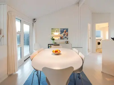 a white dining room with a white table and chairs at Holiday Home Fenneke - 50m from the sea by Interhome in Blokhus