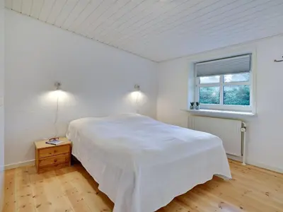 a white bedroom with a large bed and a window at Holiday Home Pelle - 800m from the sea by Interhome in Blokhus