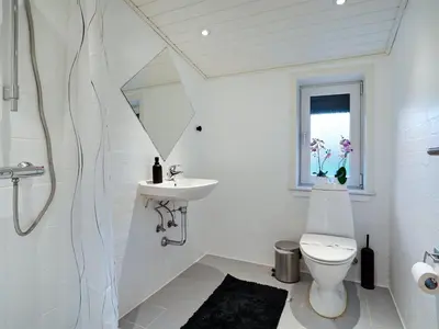 a white bathroom with a toilet and a sink at Holiday Home Pelle - 800m from the sea by Interhome in Blokhus