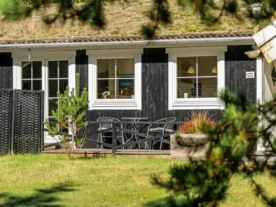 a black house with a table and chairs on the porch at Holiday Home Eimi - 1-5km from the sea by Interhome in Blokhus