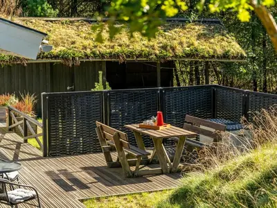 a wooden table and chairs on a wooden deck at Holiday Home Eimi - 1-5km from the sea by Interhome in Blokhus