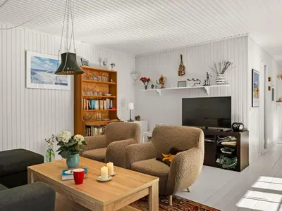 a living room with two chairs and a television at Holiday Home Eimi - 1-5km from the sea by Interhome in Blokhus