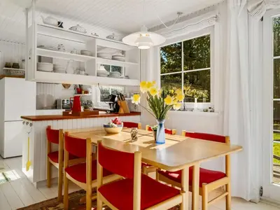 a kitchen with a wooden table and red chairs at Holiday Home Eimi - 1-5km from the sea by Interhome in Blokhus