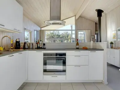 a kitchen with white cabinets and a large window at Holiday Home Anahi - 3km from the sea by Interhome in Blokhus