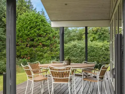 a porch with a wooden table and chairs at Holiday Home Onta - 900m from the sea by Interhome in Blokhus