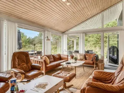 a living room with leather furniture and large windows at Holiday Home Helene - 1-5km from the sea by Interhome in Blokhus