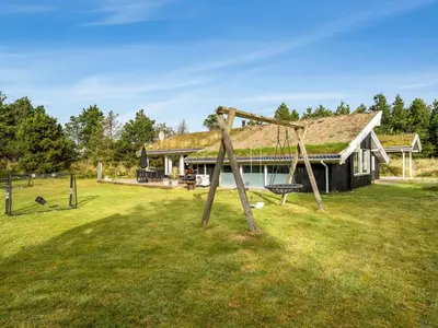a swing in a yard in front of a house at Holiday Home Helene - 1-5km from the sea by Interhome in Blokhus