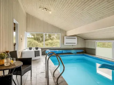 a swimming pool in a room with a table and chairs at Holiday Home Helene - 1-5km from the sea by Interhome in Blokhus