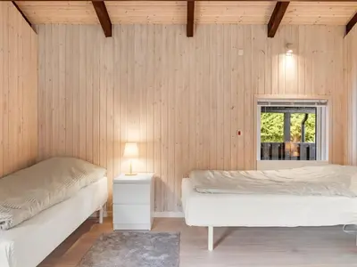 two beds in a room with wooden walls at Holiday Home Ingimar - 2-2km from the sea by Interhome in Blokhus