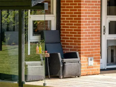 a wicker chair sitting on the porch of a house at Holiday Home Ingimar - 2-2km from the sea by Interhome in Blokhus