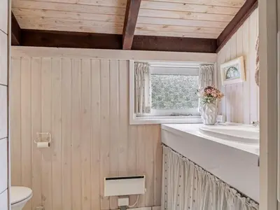 a bathroom with wooden walls and a vase of flowers at Holiday Home Ingimar - 2-2km from the sea by Interhome in Blokhus