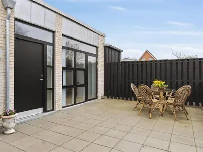 a patio with a table and chairs and a fence at Holiday Home Klaudius - 2km from the sea by Interhome in Blokhus