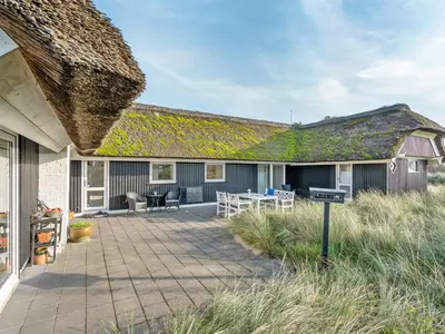 a house with a grass roof with a patio at Holiday Home Henric - 100m from the sea by Interhome in Blokhus