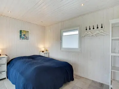 a bedroom with a blue bed and a window at Holiday Home Henric - 100m from the sea by Interhome in Blokhus
