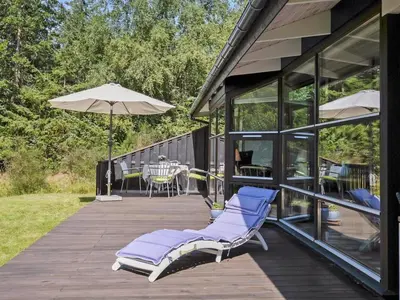 a deck with two lounge chairs and an umbrella at Holiday Home Angja - 800m from the sea by Interhome in Blokhus