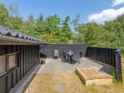a patio with a table and chairs and a fence at Holiday Home Angja - 800m from the sea by Interhome in Blokhus