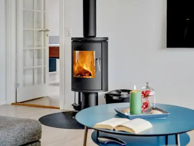 a stove in a living room with a table with a candle at Holiday Home Ancel - 1-7km from the sea by Interhome in Blokhus