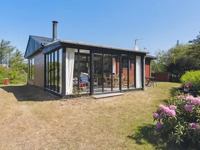 a small house with glass doors on a yard at Holiday Home Lykka - 950m from the sea by Interhome in Blokhus