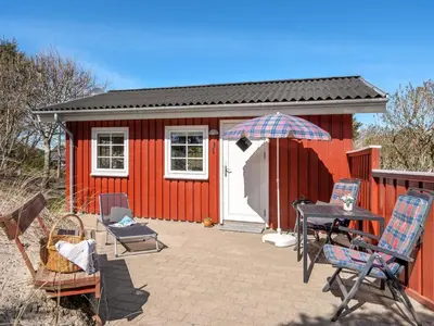 a red shed with chairs and an umbrella in front of it at Holiday Home Amie - 800m from the sea by Interhome in Blokhus