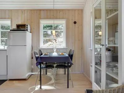 a kitchen with a table with chairs and a refrigerator at Holiday Home Amie - 800m from the sea by Interhome in Blokhus