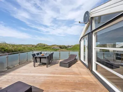 a large deck with a table and chairs on the water at Holiday Home Swerting - 230m from the sea by Interhome in Saltum