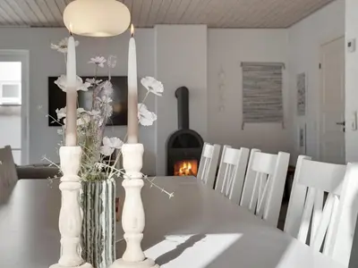 a dining room table with white candles and a fireplace at Holiday Home Riki - 150m from the sea by Interhome in Blokhus
