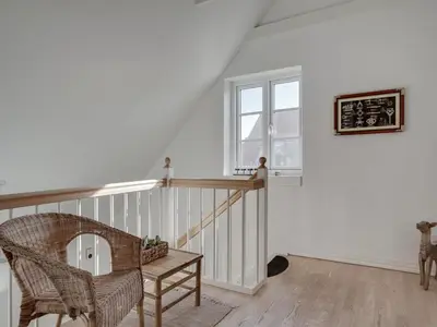 a room with a staircase with a chair and a window at Holiday Home Riki - 150m from the sea by Interhome in Blokhus