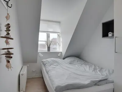 a white bedroom with a bed and a window at Holiday Home Riki - 150m from the sea by Interhome in Blokhus