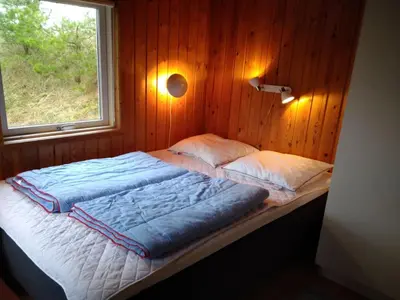 a bed in a wooden room with a window at Holiday Home Hereth - 700m from the sea by Interhome in Saltum