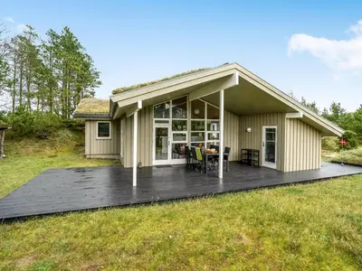 a house with a wooden deck in the yard at Holiday Home Hereth - 700m from the sea by Interhome in Saltum