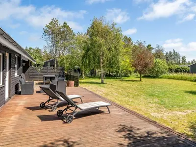 a wooden deck with two lounge chairs on it at Holiday Home Gerwin - 3km from the sea by Interhome in Blokhus