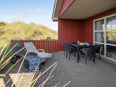 a patio with a table and chairs next to a red building at Holiday Home Dana - 290m from the sea by Interhome in Saltum