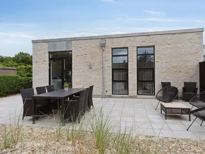 a patio with a table and chairs and a building at Holiday Home Laulu - 2km from the sea by Interhome in Blokhus
