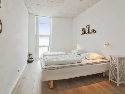 a bed in a white room with a large window at Holiday Home Laulu - 2km from the sea by Interhome in Blokhus