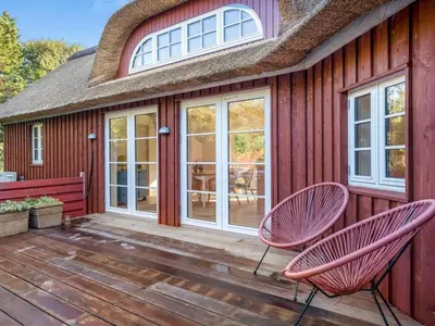 two pink chairs sitting on the deck of a house at Holiday Home Beghel - 350m from the sea by Interhome in Blokhus