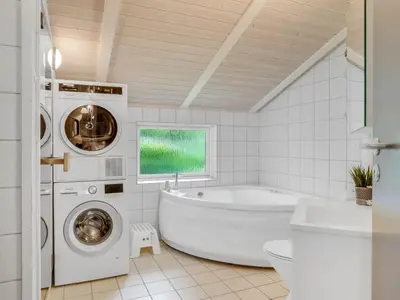 a white bathroom with a tub and a washing machine at Holiday Home Barnet - 2-2km from the sea by Interhome in Blokhus