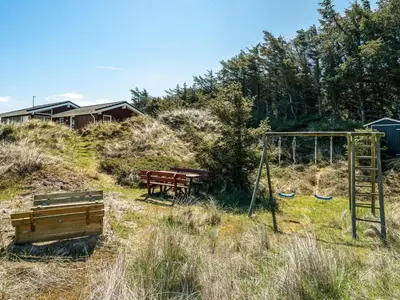 a playground with a swing set and a bench at Holiday Home Sighwarth - 350m from the sea by Interhome in Saltum