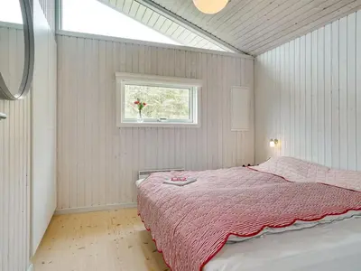 a bedroom with a bed with a pink blanket and a window at Holiday Home Erwith - 50m from the sea by Interhome in Blokhus