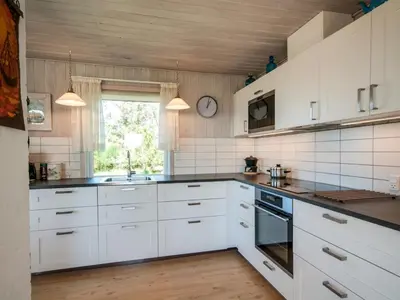 a kitchen with white cabinets and a sink and a window at Holiday Home Diuri - 400m from the sea by Interhome in Saltum