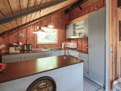 a kitchen with white cabinets and a wooden wall at Holiday Home Maritha - 950m from the sea by Interhome in Saltum